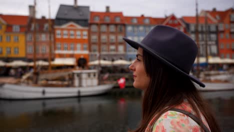 woman with a hat admiring the beauty of a canal with boats in nyhavn, denmark