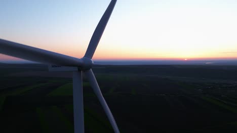 A-wind-turbine-in-a-field-at-sunset-with-a-distant-horizon