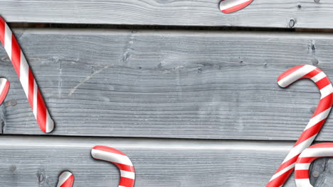 animation of christmas candy canes over wooden background with copy space