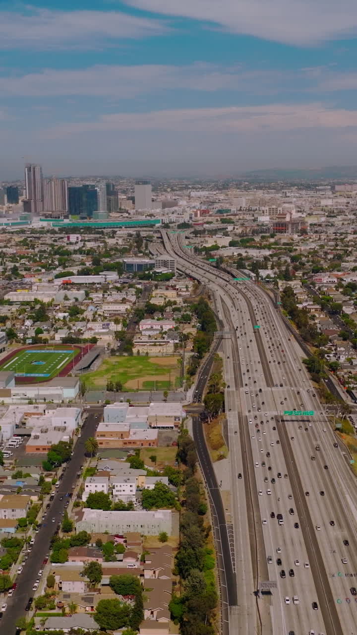 Wide busy road with numerous cars moving to and from financial downtown. Beautiful skyscrapers standing out at backdrop of blue cloudy sky. Vertical video