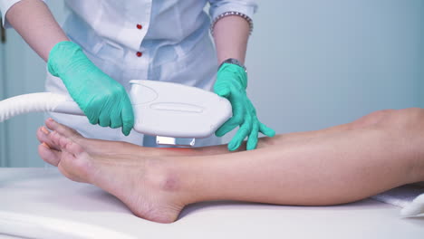 cosmetologist-does-laser-epilation-on-client-leg-in-salon