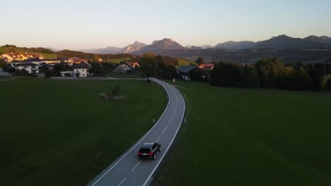 black suv car drives towards mountains at sunset setting in austria