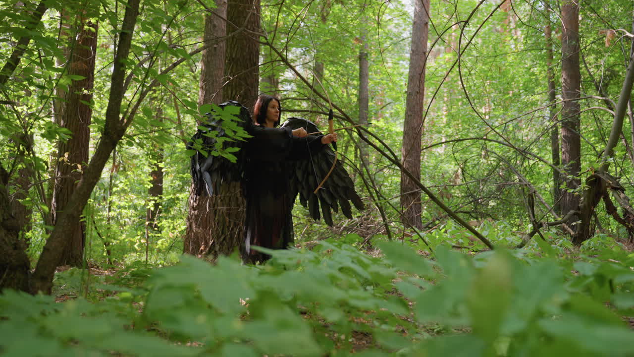 Side view of fallen black fairy goddess with large dark wings aiming bow in dense forest, surrounded by sunlight and leaves, portraying strength, grace, and mystical power