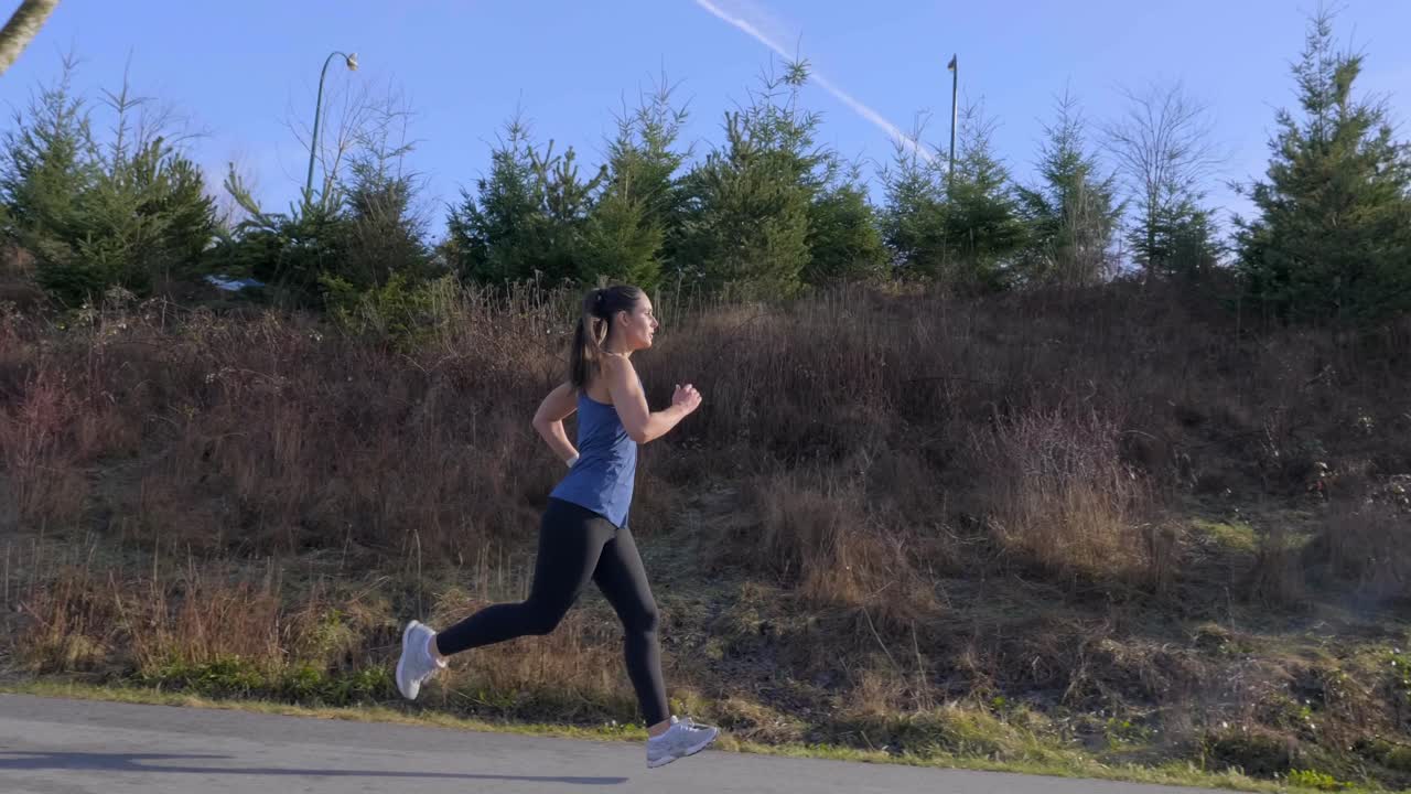 Tracking gimbal shot young athletic woman out running Slow motion