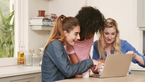 amigos felices viendo una computadora portátil mientras beben café
