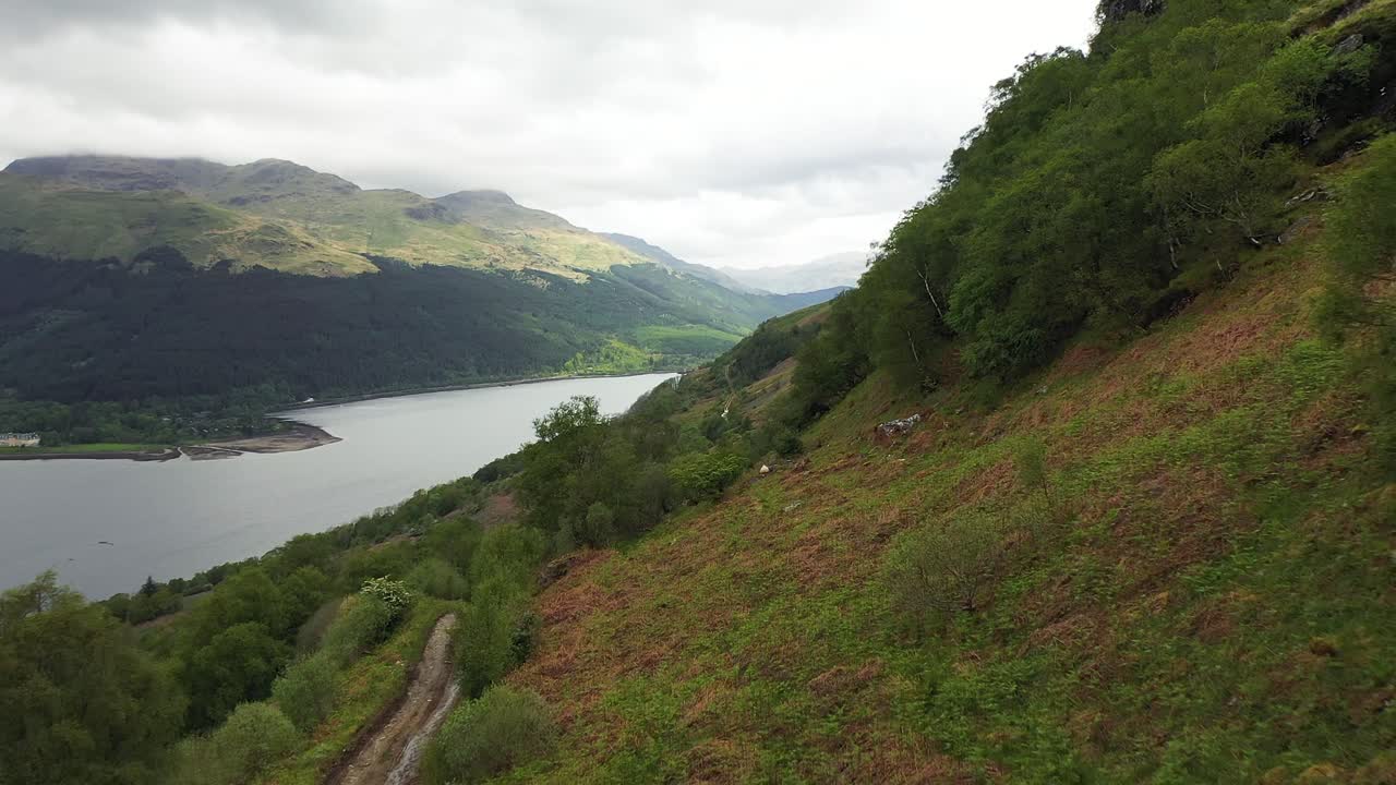 Aerial view from drone of mountain trail dirt track for 4x4s and hiking in nature, beautiful valley in Scottish highlands, Scotland, United Kingdom - flying through trees off road in the mountains