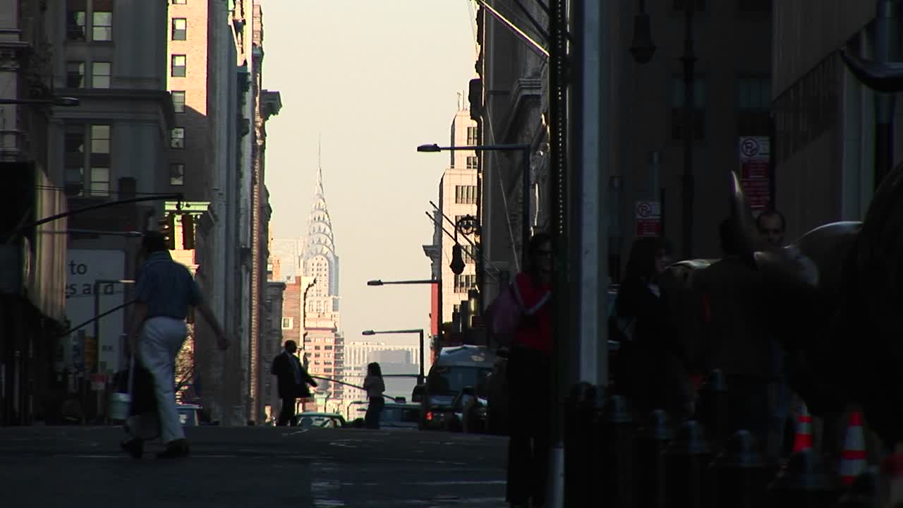 보행자가 전경에 실루엣으로 보이고 고층 빌딩이 배경에 우뚝 솟은 바쁜 거리 풍경