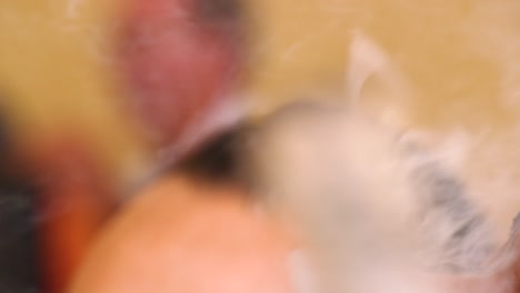 close up shot of a caribbean male smoking a nearly finished cigar as smoke fills the room