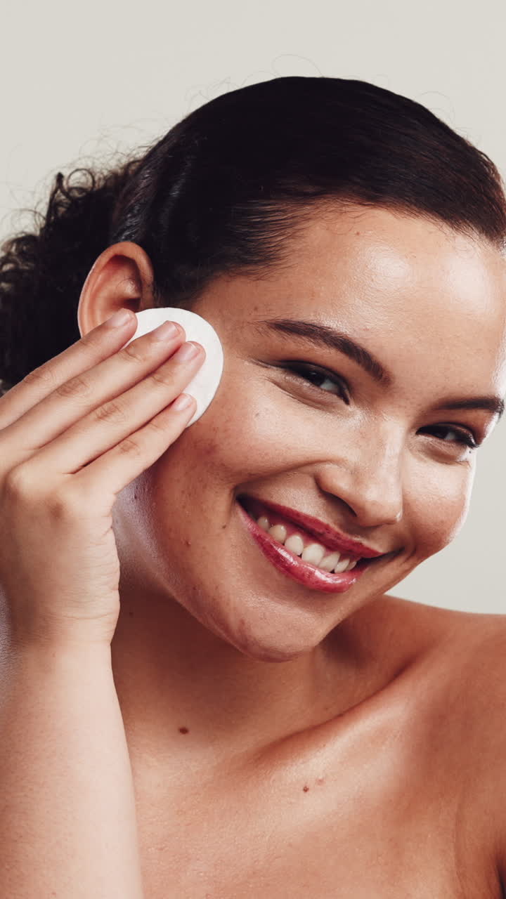 Happy Young Woman Cleansing Her Face with a Cotton Pad