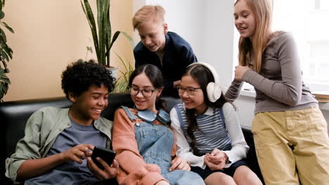 group of friends sharing a smartphone on a couch
