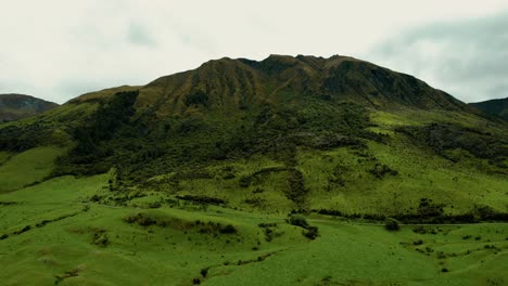 New-Zealand-Landscape-Aerial-Drone-Flying-Up-Green-Mountains-on-Lake