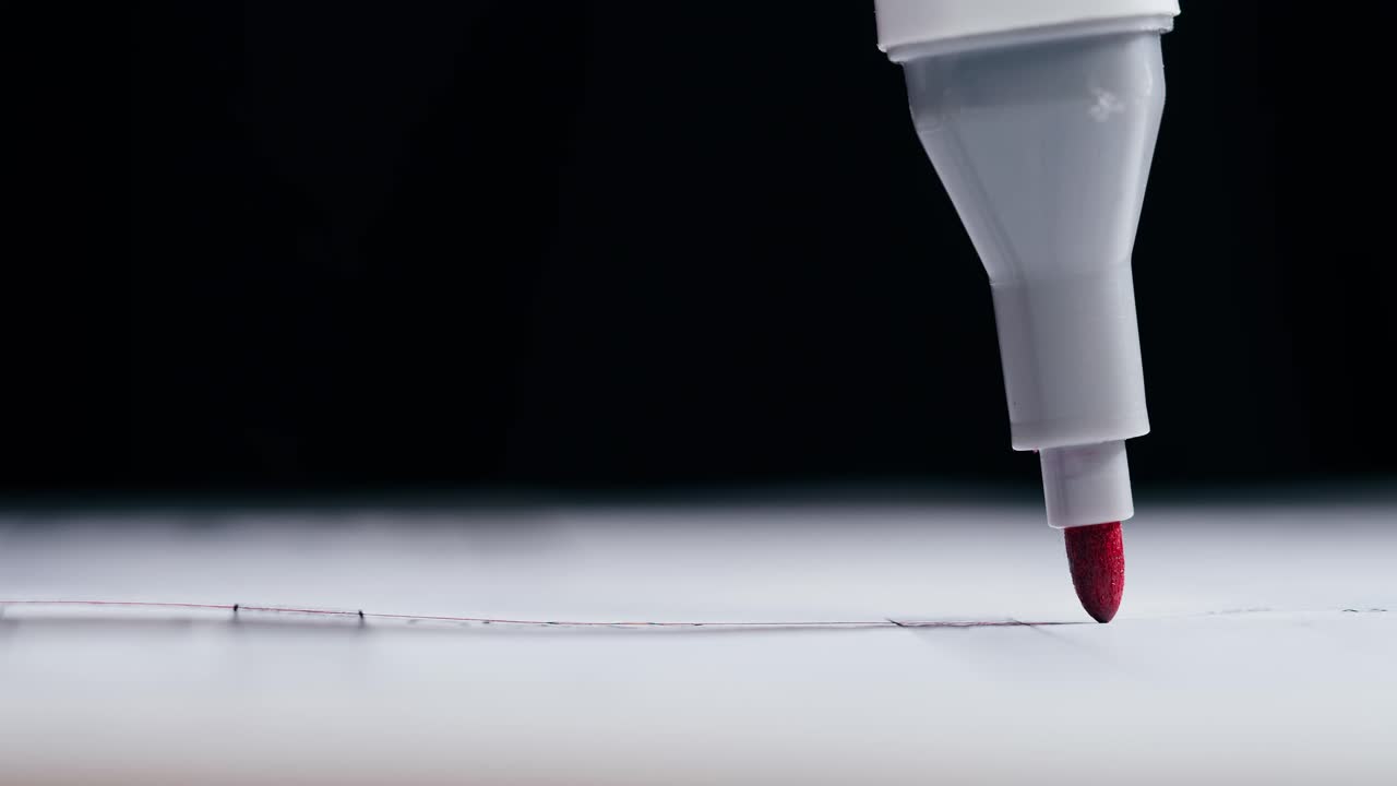 Close-up of a Red Marker Drawing a Line on White
