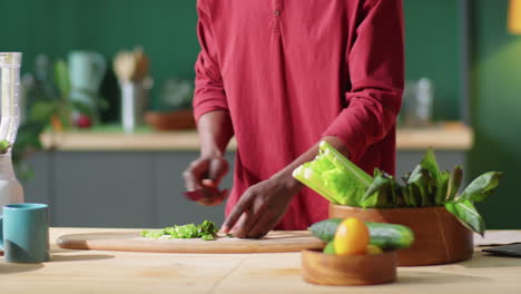 african american man cutting green salad leaves at home