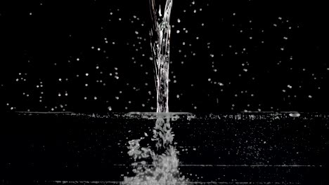 water being poured into a transparent container in slow motion