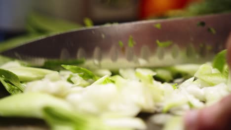 detail shot of an asian chef finely chopping leafy green vegetable with a sharp knife