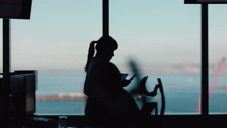 silhouette-business-woman-using-smartphone-walking-through-office-texting-sending-messages-successful-female-executive-checking-emails-on-mobile-phone-in-workplace
