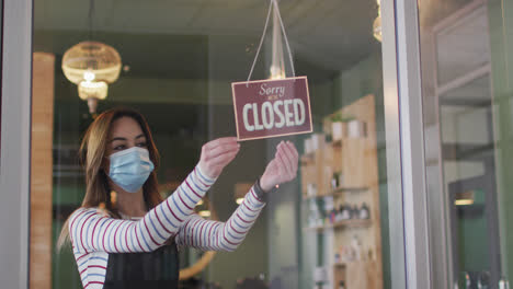 female hairdresser wearing face mask changing sign board closed to open at hair salon