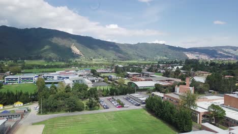 Vista-Aérea-Por-Drones-Del-Estacionamiento-De-Automóviles-En-Un-Pequeño-Pueblo-Rodeado-De-Montañas-Naturales