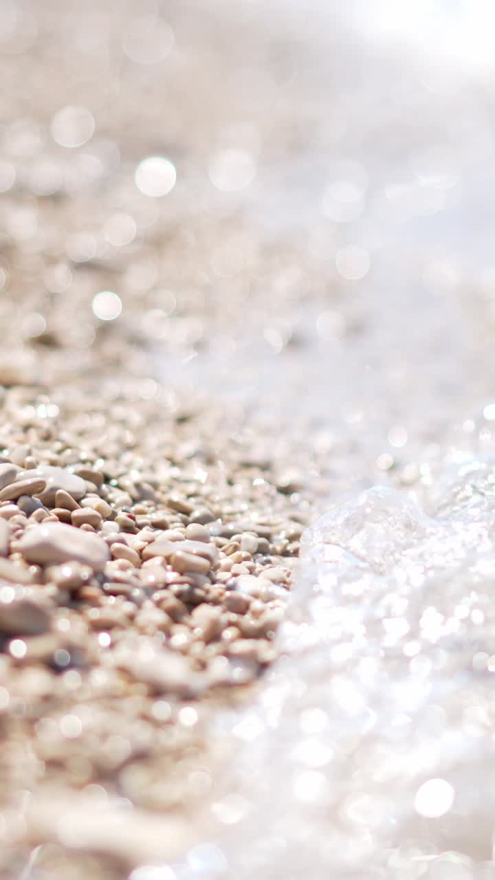 Onde delicate che lambiscono ciottoli scintillanti su una spiaggia assolata