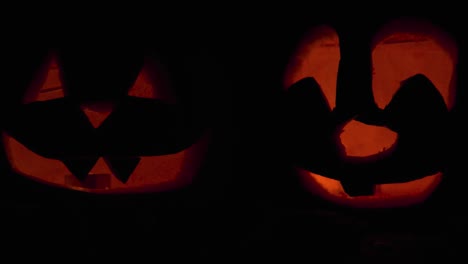 Happy-Halloween-2-Jack-O'-Lanterns-glowing-in-the-dark-wishing-Happy-Halloween:-carved-Pumpkin-decorations-with-burning-candles-inside