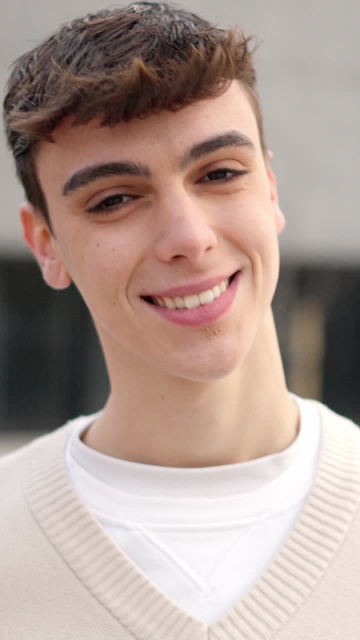 Cool caucasian young man looking at camera and smiling outdoors