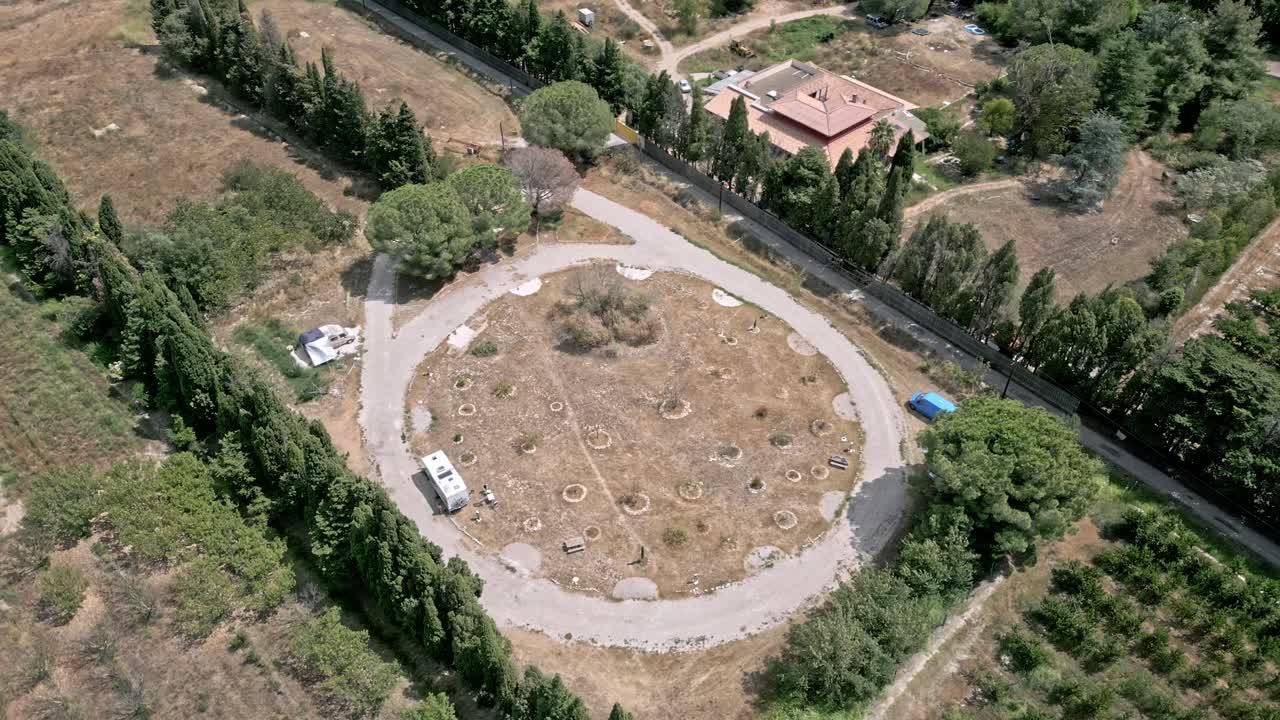 Aerial views showcase a camper van parking within a circular road, surrounded by lush trees and vibrant vegetation, creating a serene and picturesque natural setting