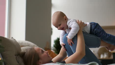 family, motherhood and people concept - happy mother kissing little baby boy over holidays lights background