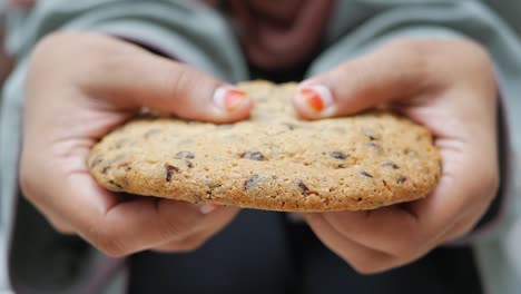 close up of a woman holding a chocolate chip cookie