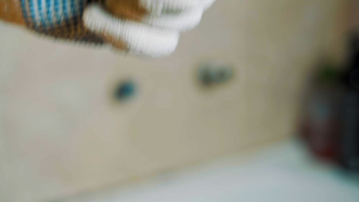 Close-up gloved hands a man is sealing tape wrap around iron water tap screw