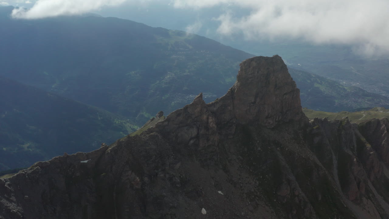 drone volando sobre la ladera de una montaña rocosa y revelando un valle verde