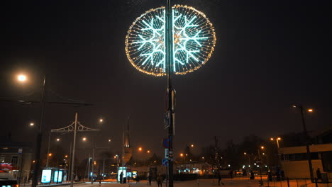 decoración navideña de copo de nieve en la calle con personas en la distancia