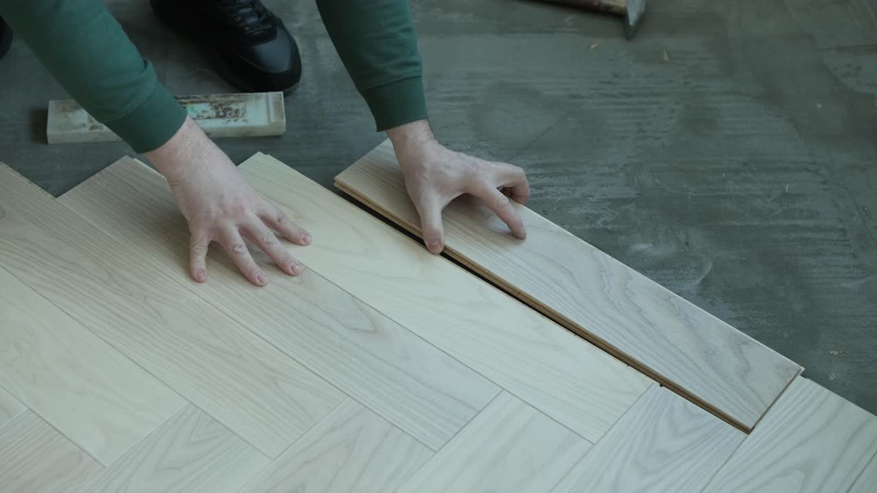 trabajador instalando pisos de madera con martillo y bloque de golpeo