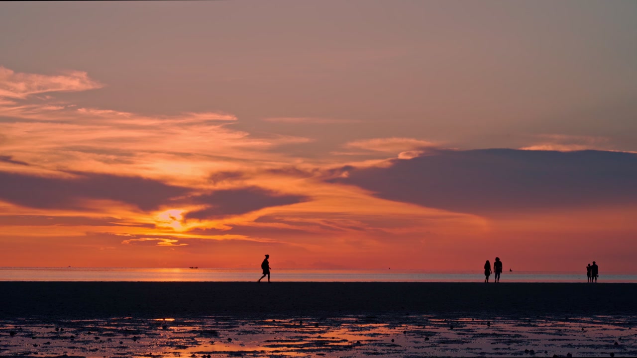 Silhouette di persone che camminano sulla spiaggia al tramonto