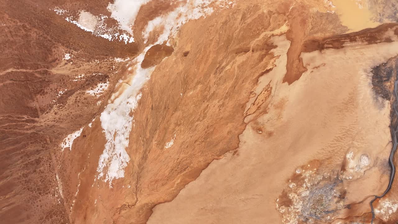 Top-down aerial view of Námafjall geothermal area in Hverarönd, Iceland. Boiling mud pools, sulfur deposits, and vivid mineral patterns form an alien, Mars-like volcanic landscape.
