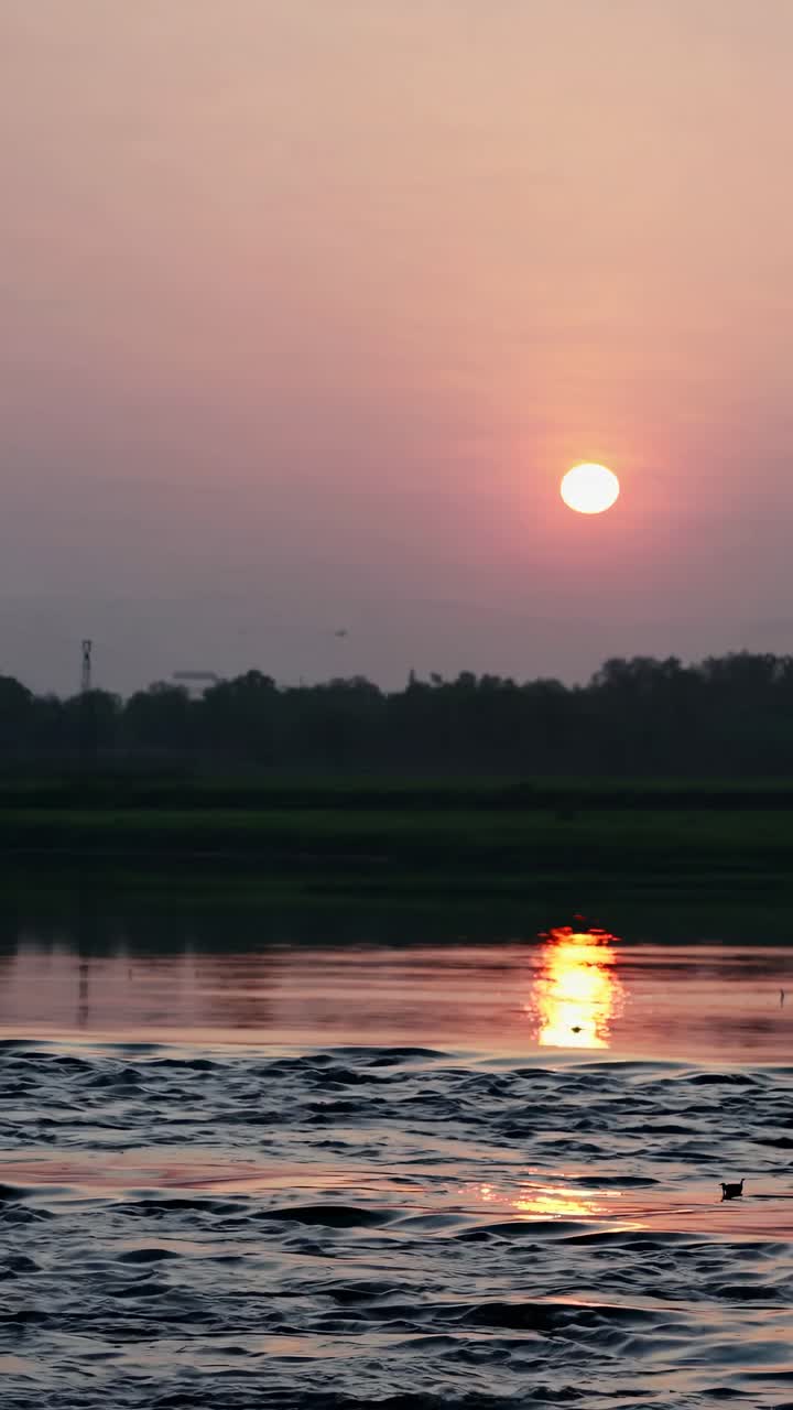 A serene sunset over a tranquil river, captured at eye level