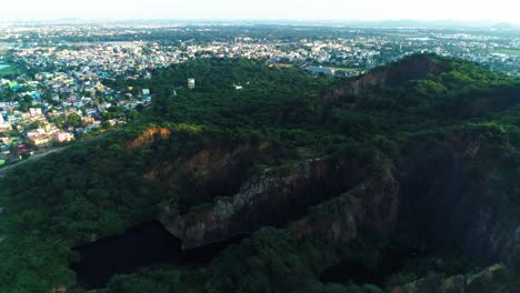 Drone-shot-showing-the-city-with-its-roads,-houses-and-lakes-with-a-forward-movement-with-a-mountain-in-foreground