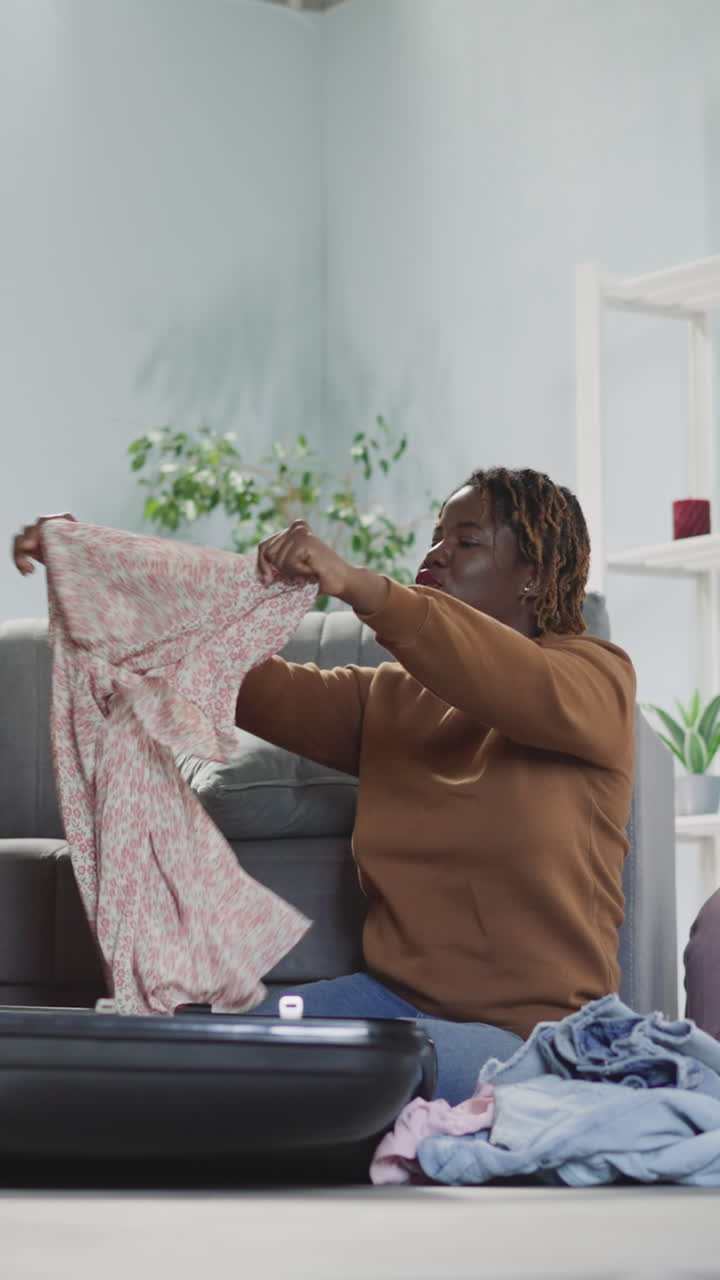 amigas multinacionais felizes colocam vestidos de verão em malas turísticas sentadas no chão. mulheres indianas e afro-americanas se preparam para viajar para o exterior