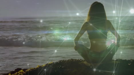 animation of networks of connections over caucasian woman praciticing yoga on beach