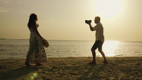 Ein-Strandfotograf-Fotografiert-Eine-Junge-Frau-Vor-Dem-Hintergrund-Des-Meeres-Und-Des-Sonnenuntergangs4k