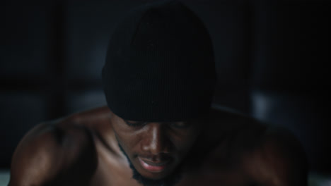 joven negro con gorra de beanie sentado en la cama dando una mirada malhumorada, primer plano