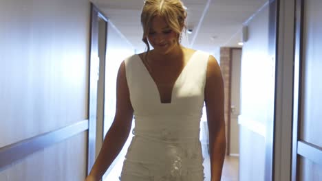 Bride-walks-down-indoor-hall-alone-smiling