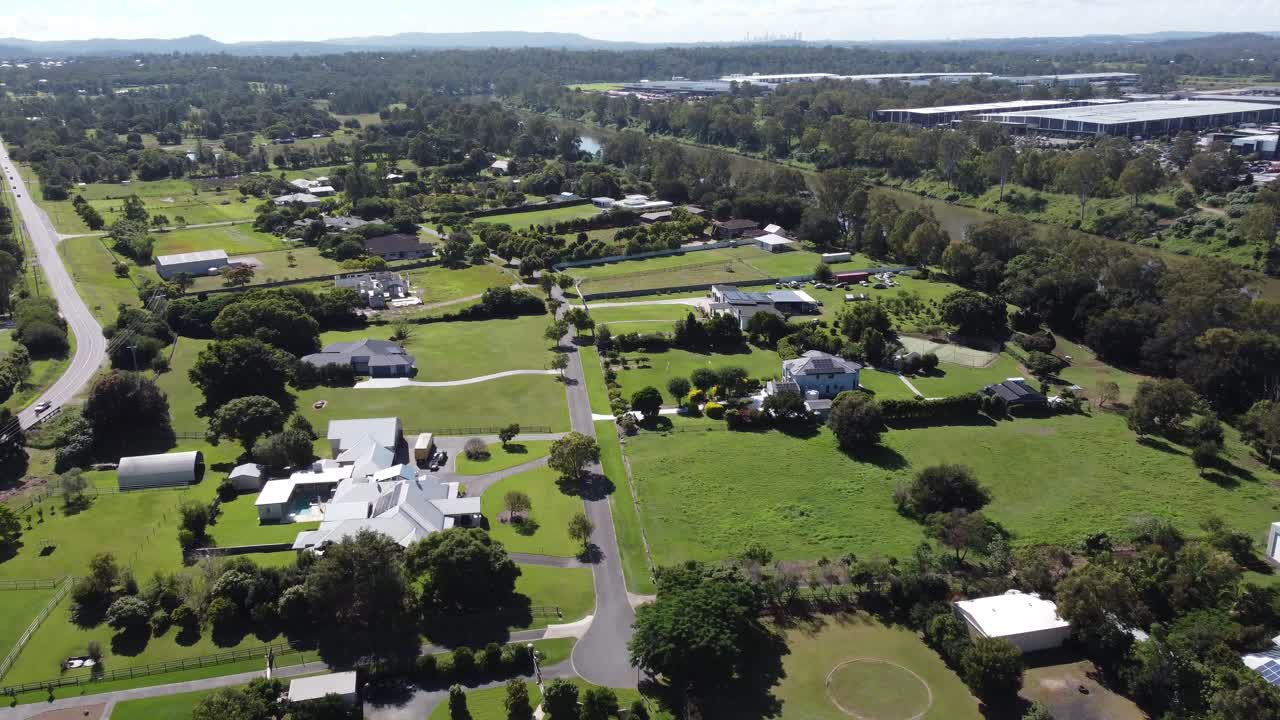 Video aereo 4K di un lussureggiante sobborgo rurale verde con grandi case unifamiliari vicino a un piccolo fiume in Australia.
