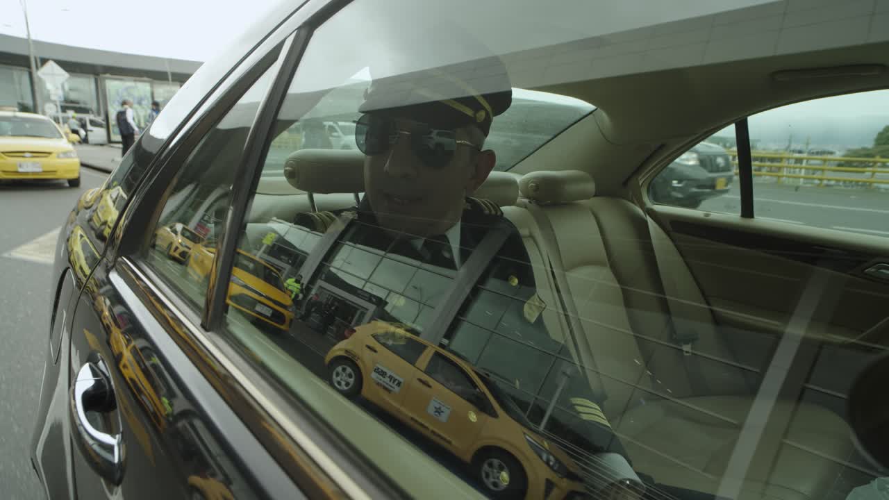 A pilot sits in a seat inside a black car that drives him