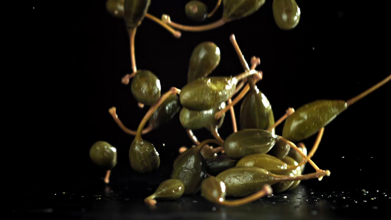 Färska kaprisbär som faller i slowmotion på svart yta