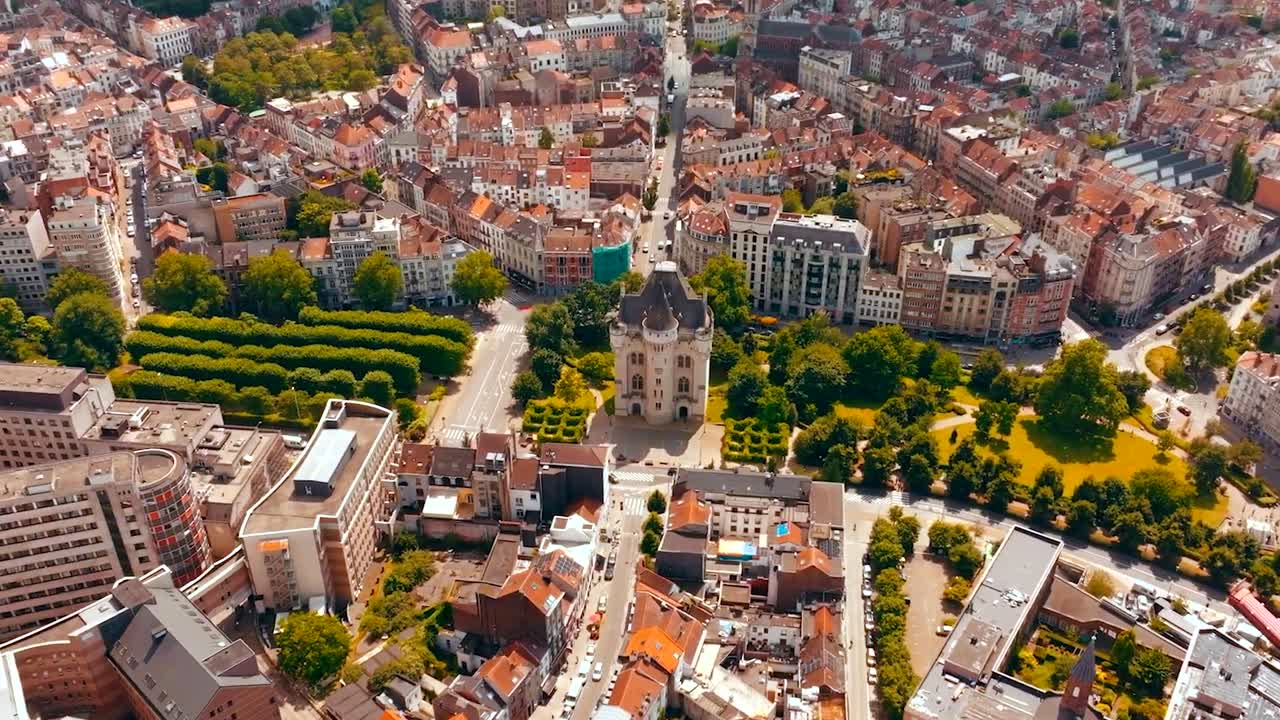 Aerial drone spinning or orbiting shot around Halle gate or the city gates of Bruxells that has medieval old architecture and is in the centre of the city that has red rooftops and modern buildings.