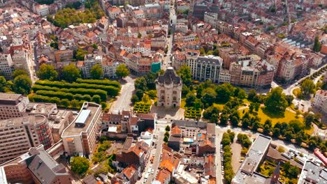 aerial drone spinning or orbiting shot around halle gate or the city gates of bruxells that has medieval old architecture and is in the centre of the city that has red rooftops and modern buildings.