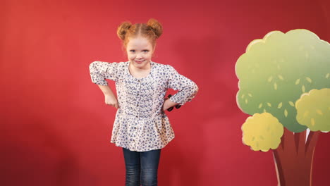 little girl with binoculars in hands posing. isolated on a red background.