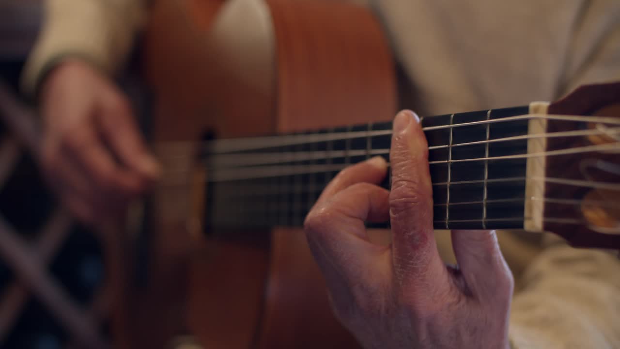 4K at 60fps (slow motion) - Man with old hands playing guitar at home - Relax and warm mood