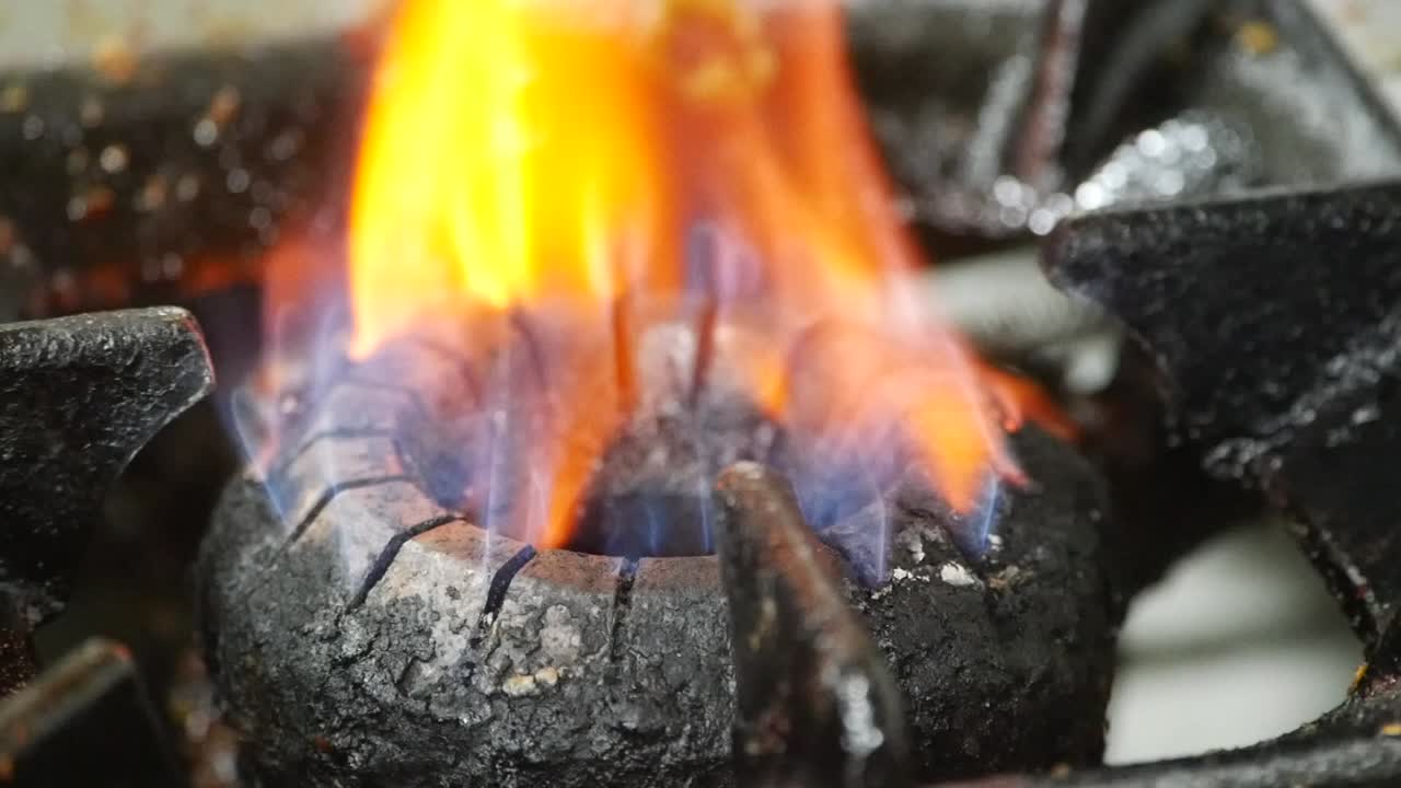 Close-up of a dirty gas stove burner with a flame
