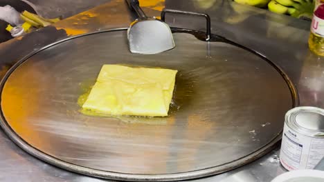 a street vendor prepares thai roti on a hot griddle in phuket, thailand, showcasing traditional street food techniques and vibrant local culture